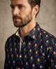 Man wearing a navy shirt with colorful floral pattern against a neutral background