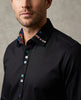 Man wearing a black dress shirt with colorful collar and brand logo.