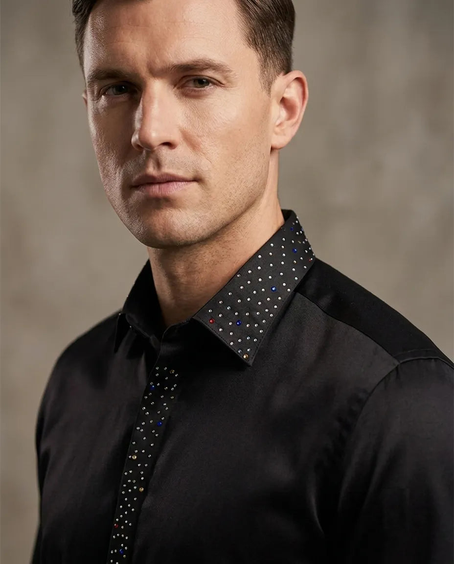 Man wearing a black shirt with a patterned collar against a neutral background