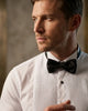 Man wearing a black bow tie and white dress shirt with a blurred background