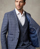 Man wearing a blue checkered suit with a white shirt against a neutral background