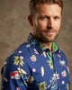 Man wearing a colorful floral shirt against a neutral background
