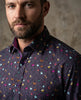 Man wearing a dark shirt with colorful butterfly pattern against a neutral background