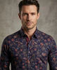 Man wearing a dark floral patterned shirt against a gray background