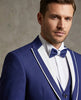 Man wearing a blue suit with a white shirt and blue bow tie against a neutral background
