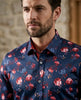 Man wearing a blue floral shirt against a stone wall background