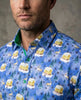Man wearing a blue patterned shirt with winter-themed designs on a gray background
