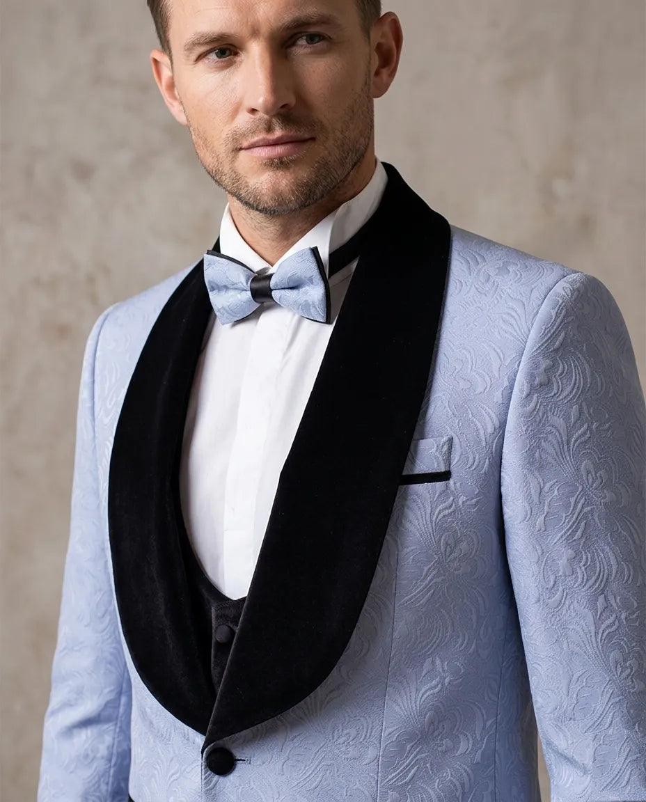 Man wearing a light blue tuxedo with black lapels and a bow tie against a neutral background