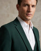Man wearing a green suit and white shirt against a beige background