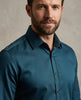 Man wearing a teal shirt against a neutral background