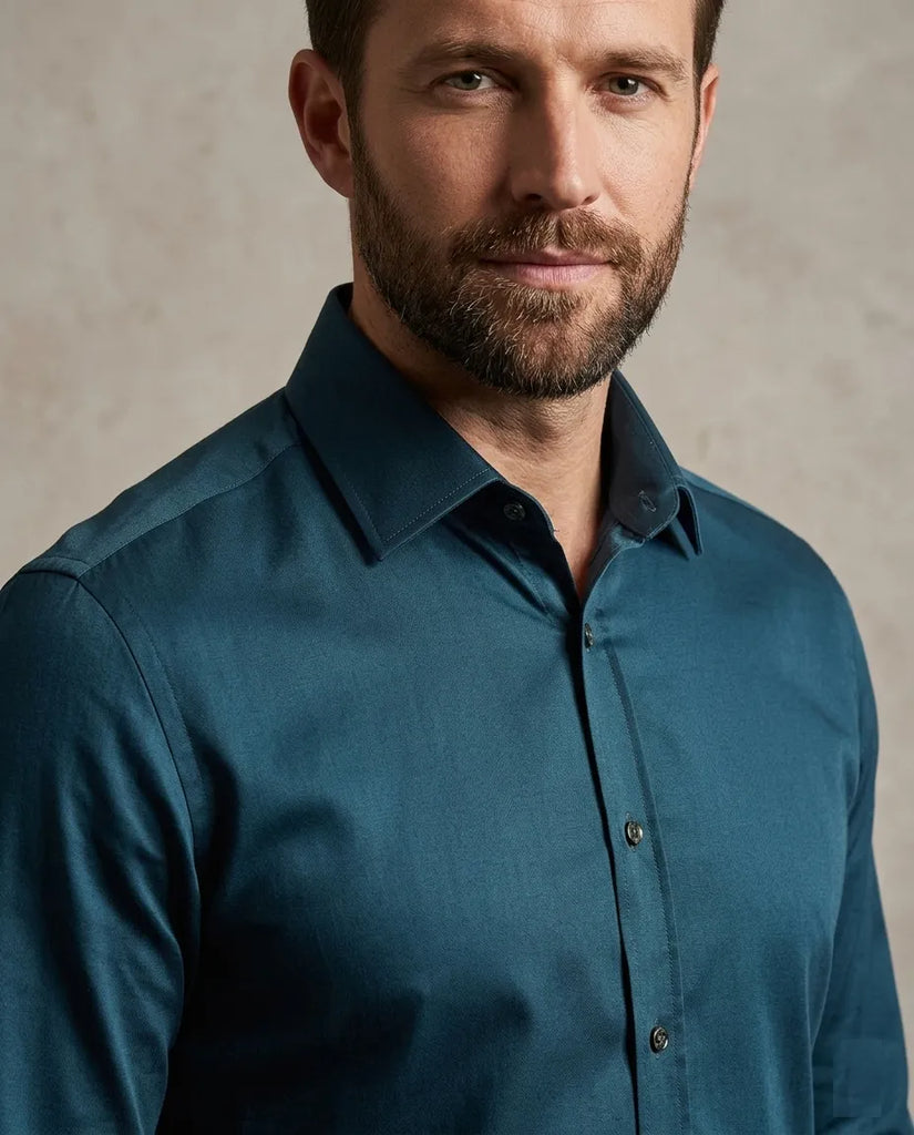 Man wearing a teal shirt against a neutral background