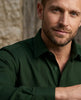 Man wearing a green shirt with a neutral background
