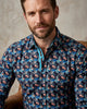 Man wearing a patterned shirt with a neutral background