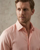 Man wearing a light pink dress shirt against a neutral background