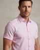 Man wearing a light pink short-sleeve shirt against a neutral background