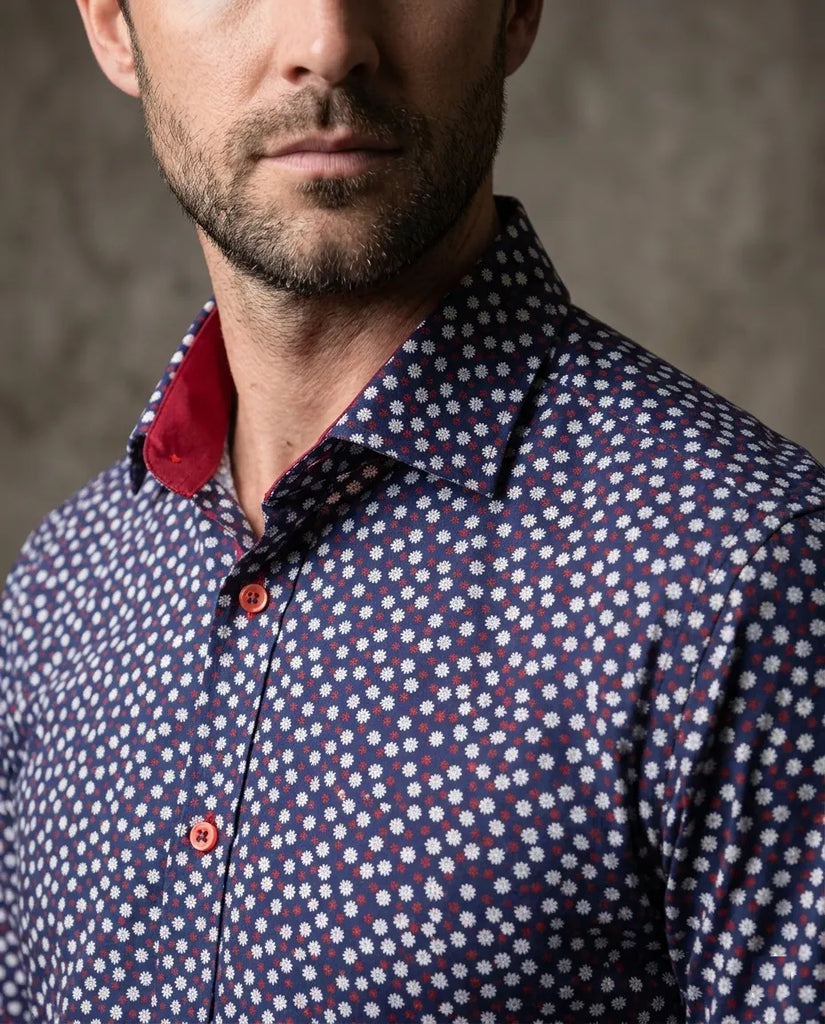 Man wearing a patterned shirt with a red collar against a neutral background