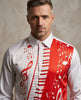 A man wearing a white long-sleeve dress shirt with a red and white musical-themed print featuring piano keys, a red treble clef, and white musical notes on a textured beige background.