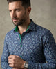 Man wearing a blue floral patterned shirt against a neutral background