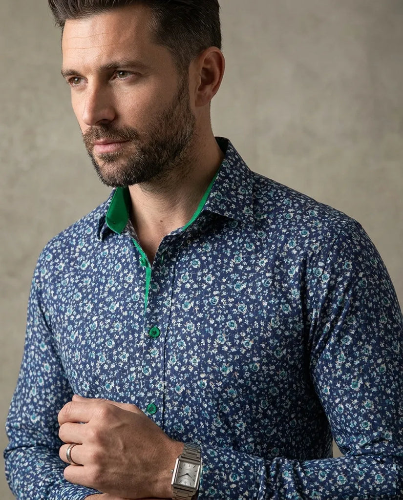 Man wearing a blue floral patterned shirt against a neutral background