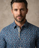Man wearing a blue patterned shirt against a beige background