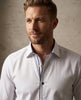 Man wearing a white dress shirt with a patterned collar against a neutral background