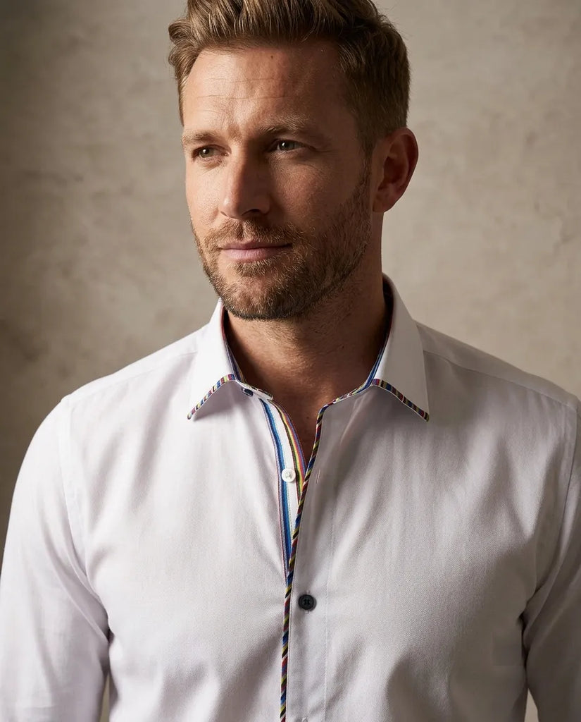 Man wearing a white dress shirt with a patterned collar against a neutral background