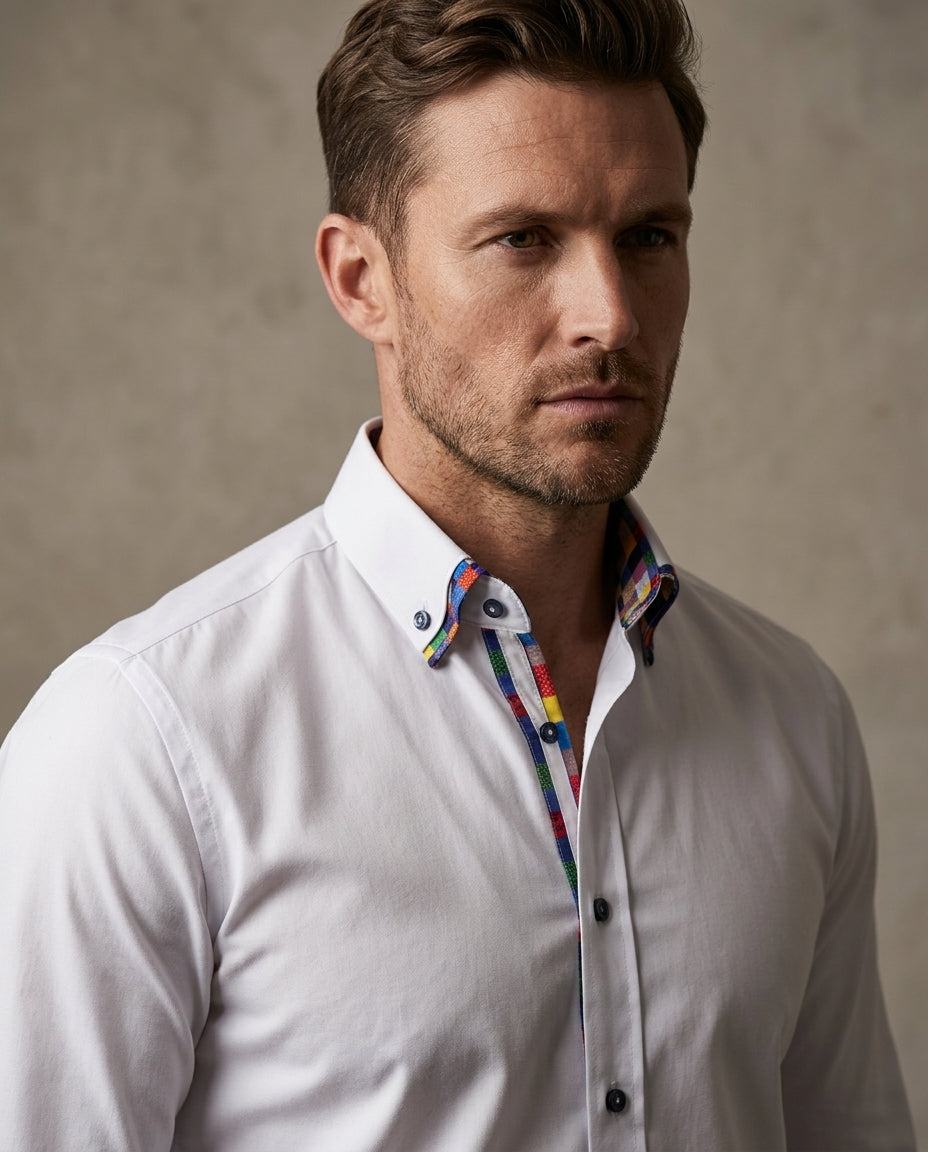A man wearing a white long-sleeve button-down shirt with a colorful patterned inner collar, photographed against a neutral textured beige background.