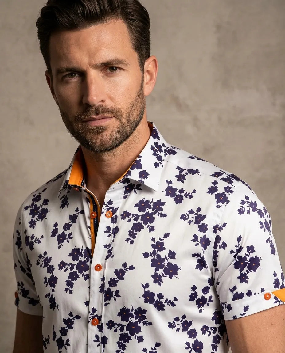 Man wearing a white floral shirt with orange accents against a beige background