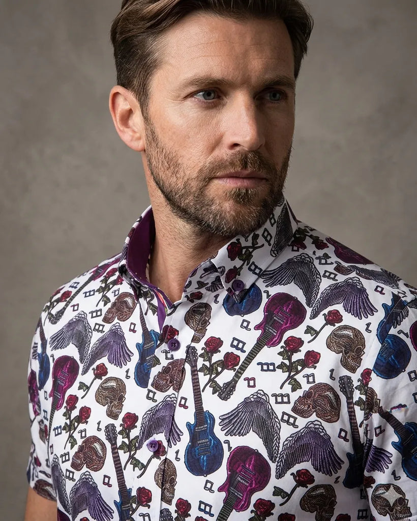 Man wearing a patterned shirt with musical instruments and skulls on a gray background