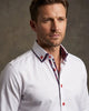 Man wearing a white dress shirt with a patterned collar and red buttons against a neutral background