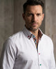 Man wearing a white shirt with a colorful collar against a neutral background