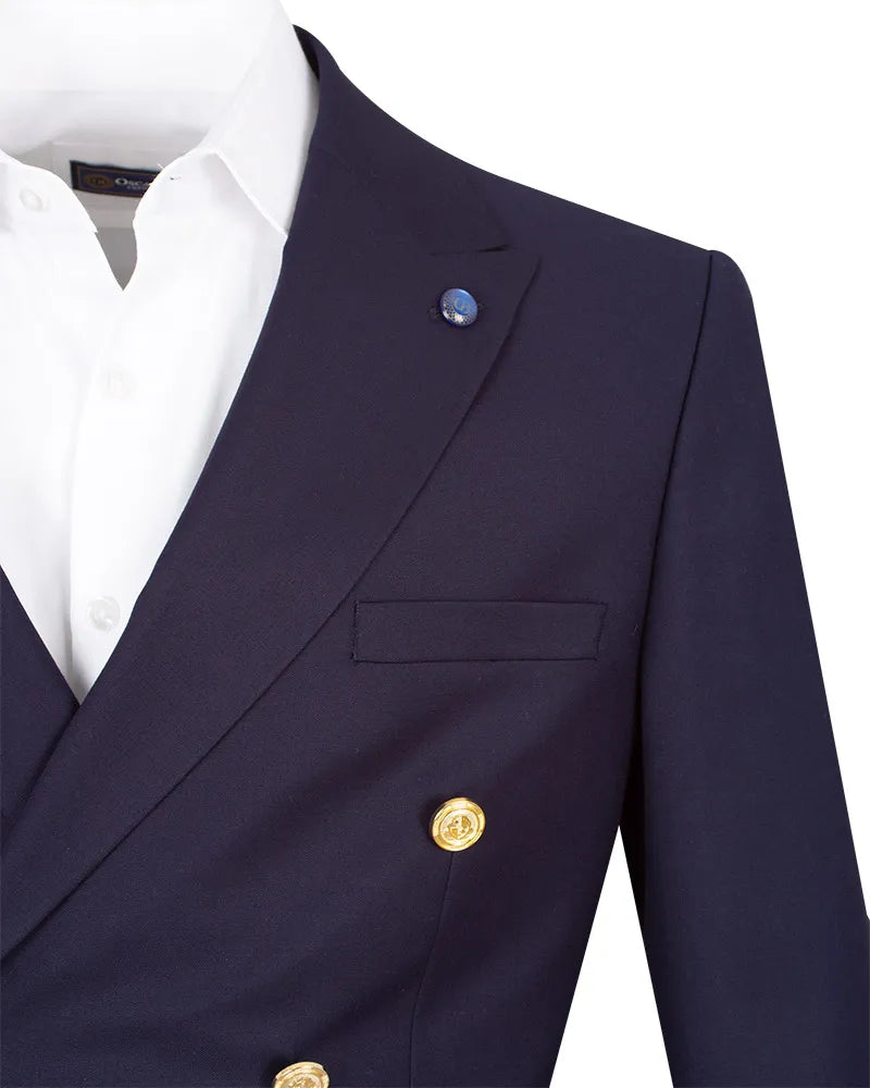 A close-up of a navy blue double-breasted blazer worn over a white dress shirt. The blazer features gold buttons and a small blue lapel pin, set against a plain white background.