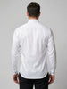 A man viewed from the back wearing a white long-sleeve dress shirt and black trousers, standing against a plain light gray studio background.